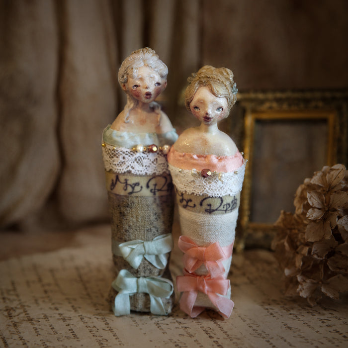 Blue- and pink-ribbon Lambwick Twin Series doll brooches displayed side by side.