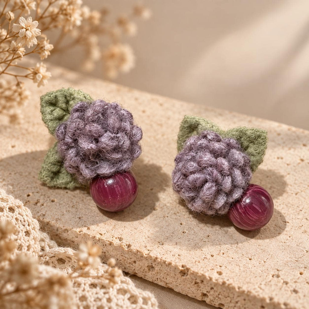 Lilac Berry lavender crochet-flower earrings arranged on textured cream stone.