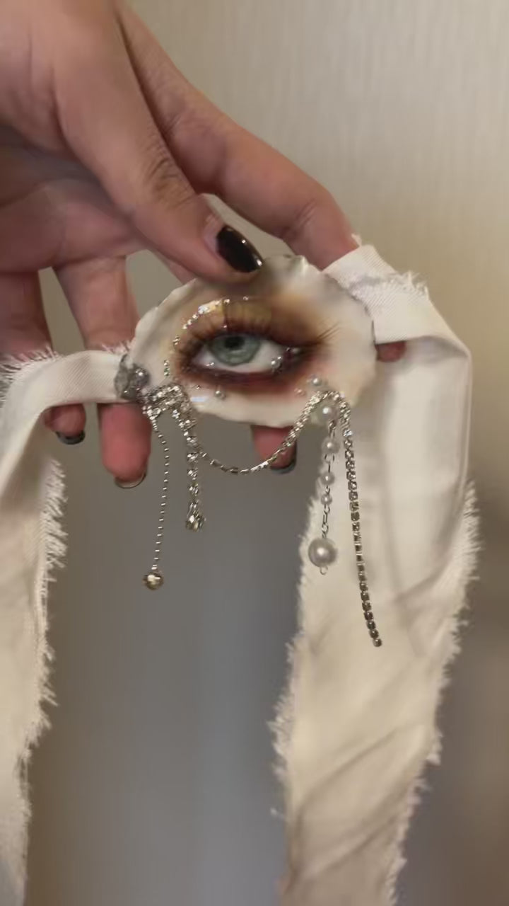Sereine Eye LV027 — handheld view showing the eye, pearl drapes and ivory ribbon