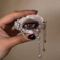 Close-up of Lilith Veil red-pupil oyster eye held in hand with pearl and silver chain drapes