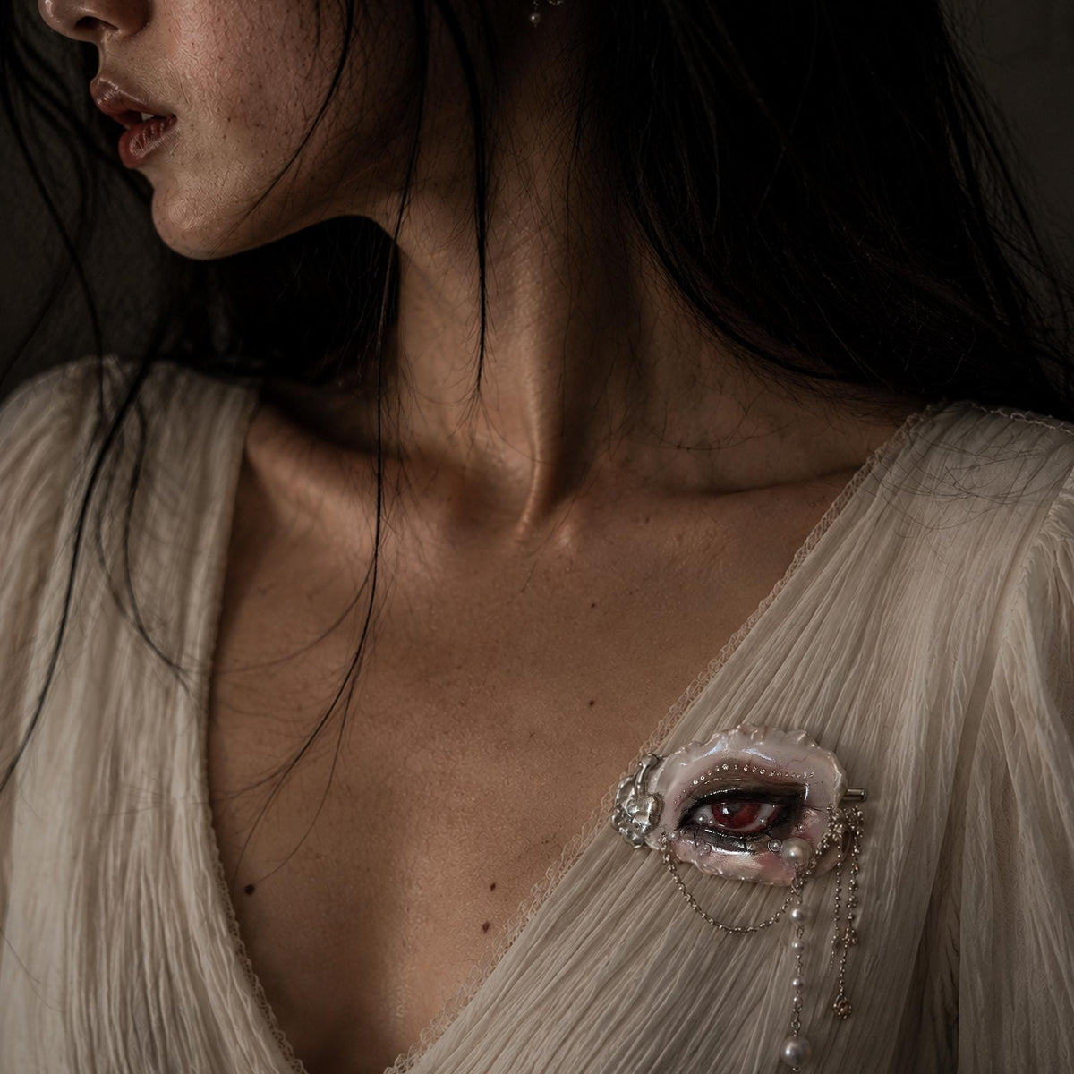 Modeled close-up wearing Lilith Veil as a brooch on ivory fabric